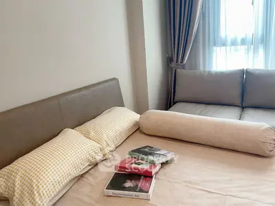 Cozy bedroom with stylish sofa and books near window, perfect for relaxation.