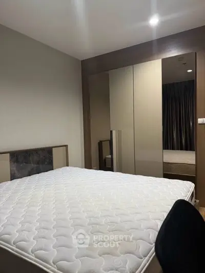 Modern bedroom with sleek mirrored wardrobe and comfortable bed in stylish apartment.