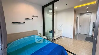 Modern bedroom with sliding glass door and cozy seating area in stylish apartment.