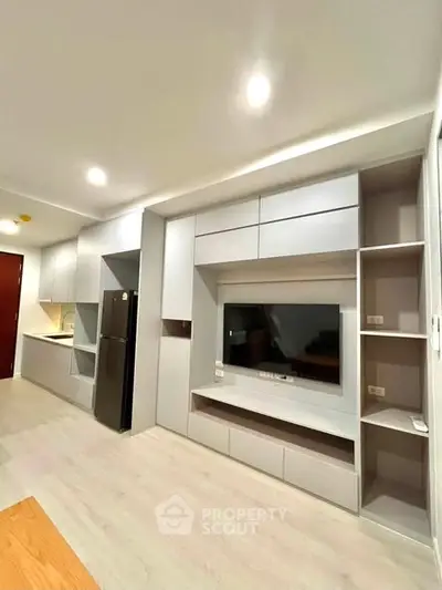 Modern living room with built-in TV unit and sleek kitchen area