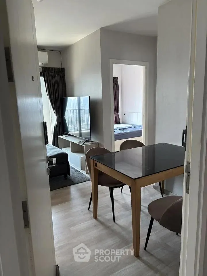 Modern apartment interior with dining area and living room featuring sleek furniture and natural light.