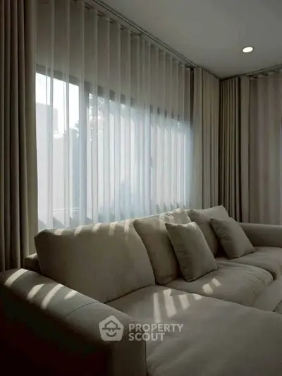 Elegant living room with plush sofa and sheer curtains, perfect for relaxation and comfort.