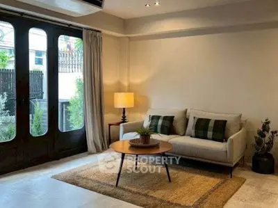 Charming living room with cozy sofa, stylish coffee table, and natural light from large windows.