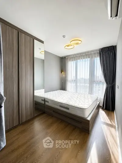 Modern bedroom with wooden flooring, large window, and stylish lighting fixtures.