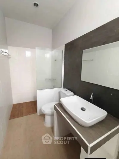 Modern bathroom with sleek design featuring a vessel sink and bathtub in a minimalist setting.