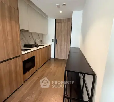 Modern kitchen with sleek wooden cabinetry and built-in appliances in a compact layout.