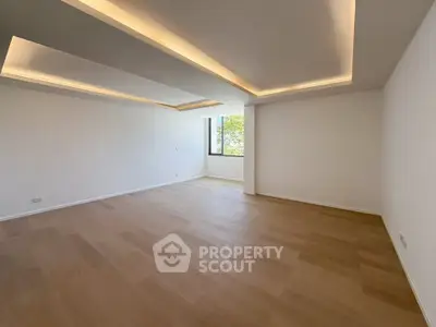 Spacious empty living room with modern ceiling lights and large window view.