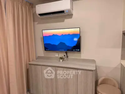 Modern living room with wall-mounted TV and air conditioning unit, featuring stylish cabinetry and cozy seating.