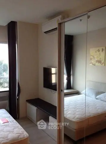 Modern bedroom with mirrored closet and wall-mounted TV in a cozy apartment.