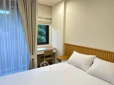 Cozy bedroom with natural light, featuring a comfortable bed and a small study desk by the window.
