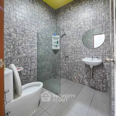 Modern bathroom with stone tile walls and glass shower partition