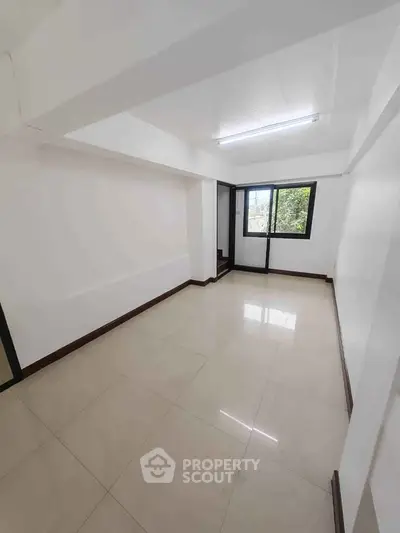 Spacious unfurnished room with large window and tiled flooring, ideal for customization.