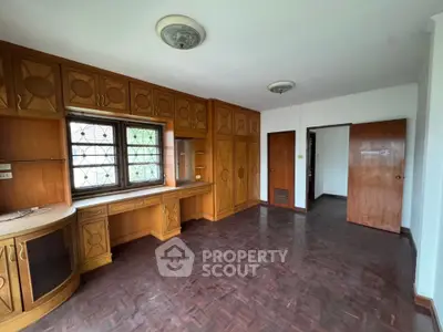 Spacious room with wooden cabinetry and parquet flooring, ideal for home office or study area.
