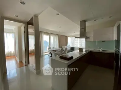 Spacious modern kitchen with open layout and dining area, featuring sleek cabinetry and ample natural light.