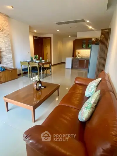 Spacious living room with leather sofa and modern dining area in open layout apartment.