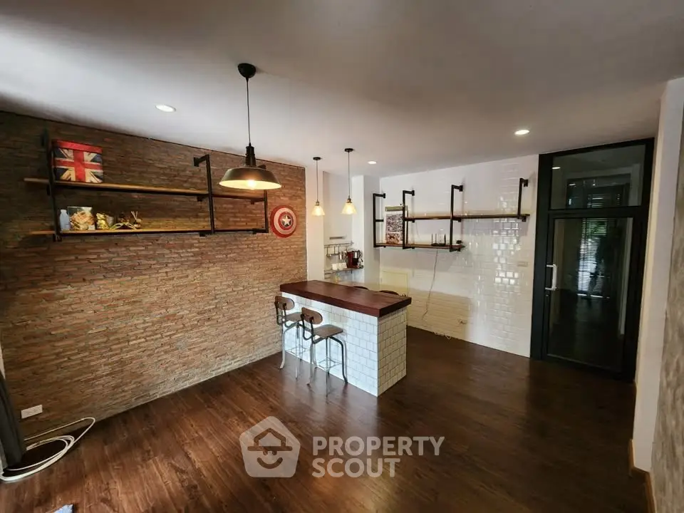 Stylish open-layout kitchen with brick accent wall and modern lighting