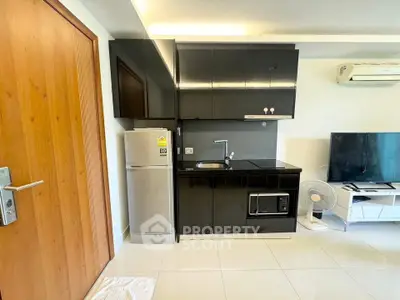 Modern compact kitchen with sleek black cabinets and stainless steel appliances in a stylish apartment.