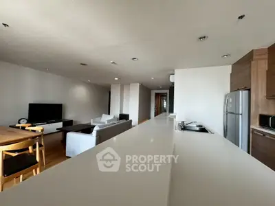 Spacious modern living room with open kitchen and sleek furnishings in a contemporary apartment.