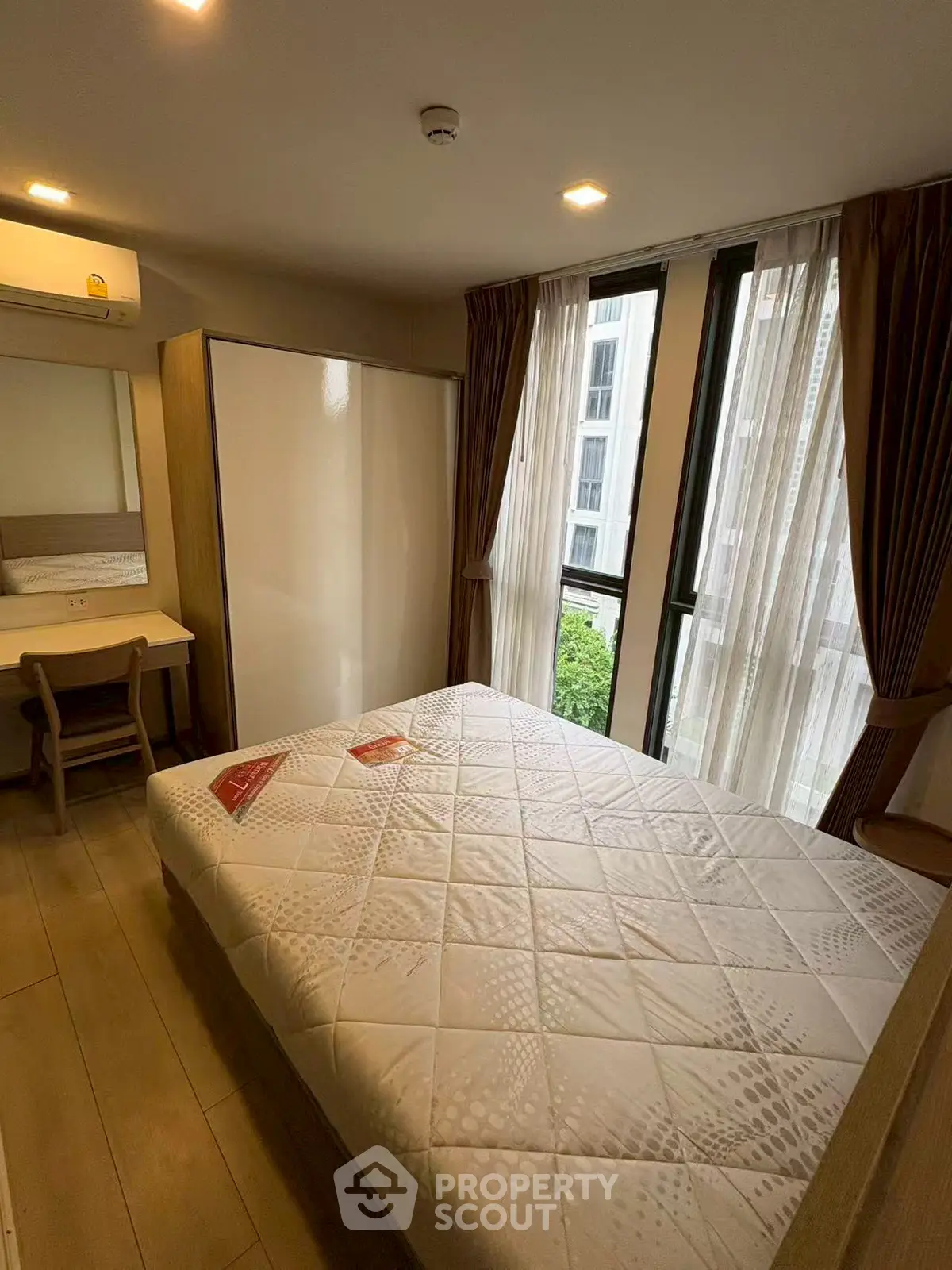 Cozy bedroom with large window and modern furnishings in a stylish apartment.