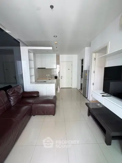 Modern living room with sleek design, featuring a leather sofa and open kitchen layout.