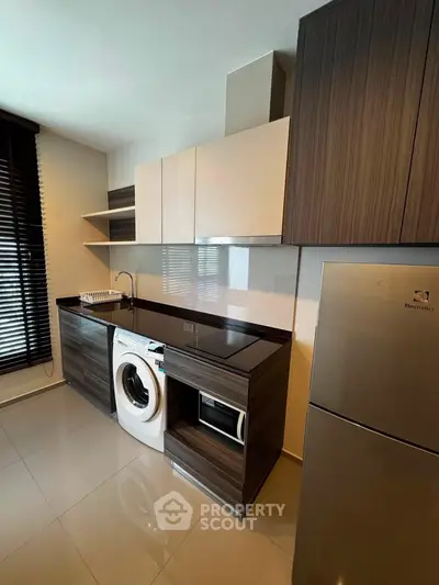 Modern kitchen with sleek cabinets, washing machine, and stainless steel fridge in a stylish apartment.