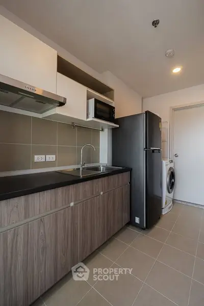 Modern kitchen with sleek cabinetry, stainless steel appliances, and washer-dryer combo.