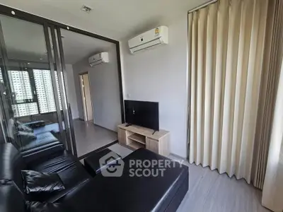 Modern living room with sleek black leather sofa and wall-mounted air conditioning.