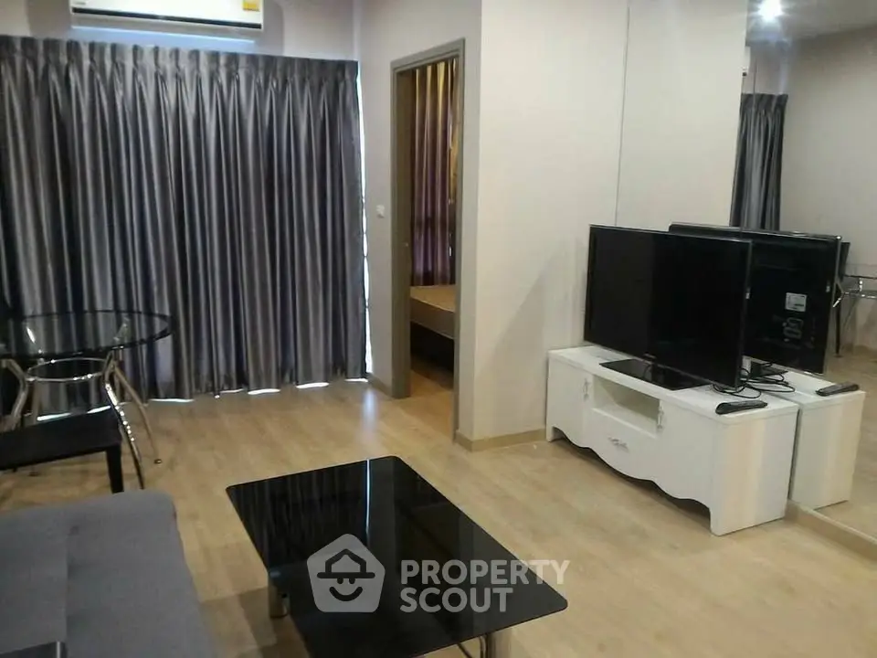 Modern living room with sleek furniture and large TV, featuring elegant curtains and wooden flooring.