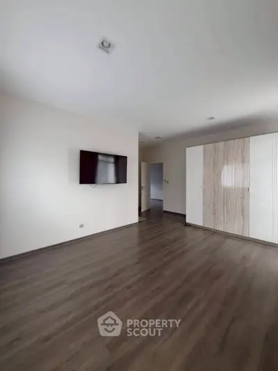 Spacious modern living room with mounted TV and sleek wooden flooring.