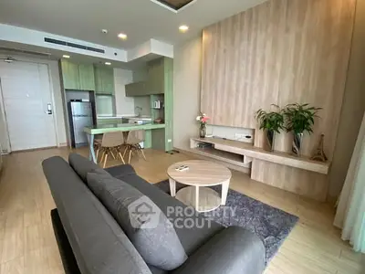 Modern living room with open kitchen, stylish decor, and cozy seating area.