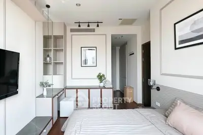 Modern bedroom with stylish decor and natural light, featuring a sleek TV and elegant furnishings.