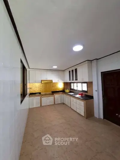 Spacious kitchen with modern cabinetry and ample natural light, perfect for culinary enthusiasts.