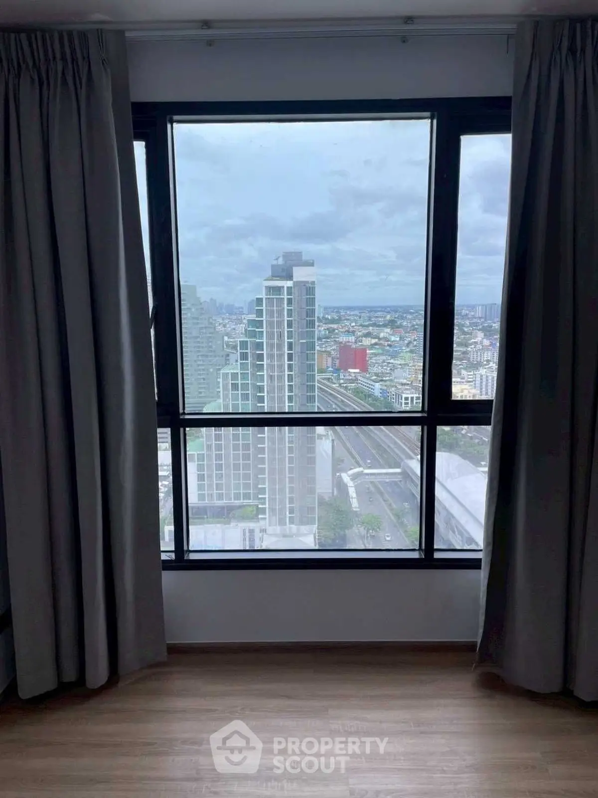 Stunning cityscape view from high-rise apartment window with elegant curtains.