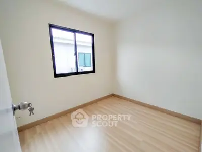 Spacious empty bedroom with large window and wooden flooring