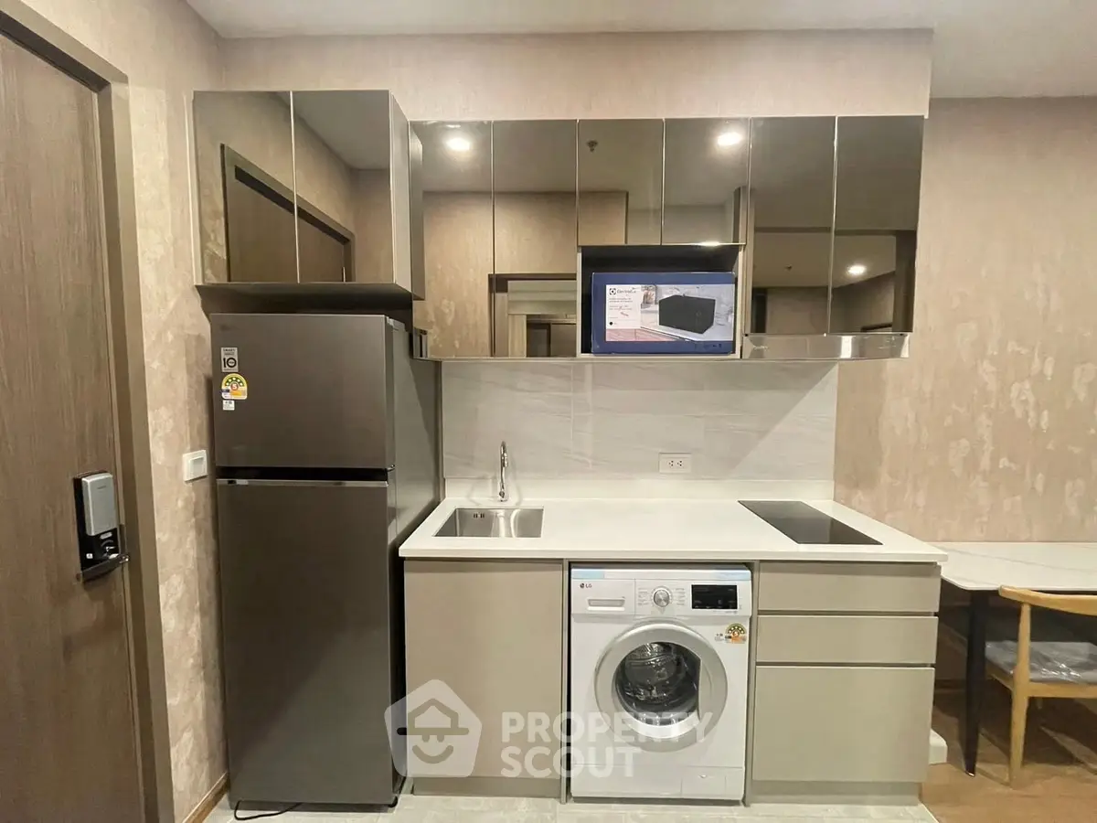 Modern kitchen with sleek appliances and mirrored cabinets in a stylish apartment.
