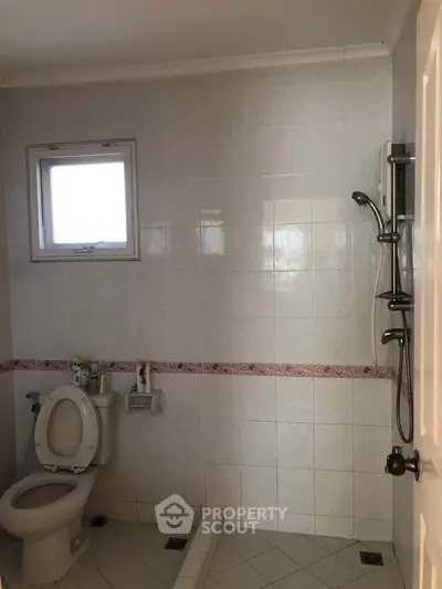 Spacious bathroom with shower and window, featuring tiled walls and floor.