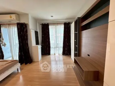 Spacious modern living room with wooden flooring and large windows for natural light.