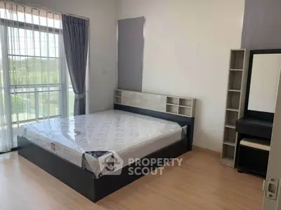 Spacious bedroom with large window and modern furnishings in a bright, airy apartment.