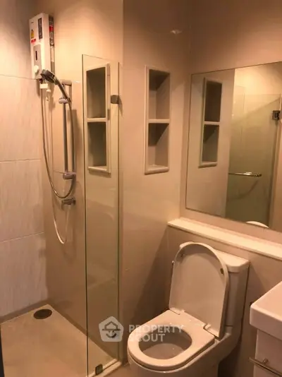 Modern bathroom with glass shower and sleek fixtures in contemporary apartment.