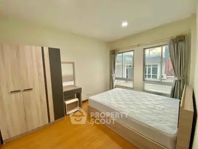 Spacious bedroom with large windows and modern furniture in a bright apartment.