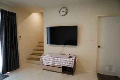 Modern living room with wall-mounted TV and staircase, minimalist decor