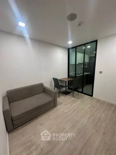 Modern living room with sleek design and open kitchen layout, featuring a cozy sofa and dining area.