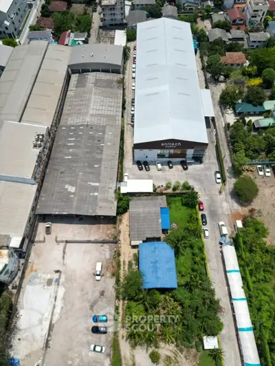 Aerial view of industrial buildings with parking and greenery, showcasing potential commercial real estate investment.