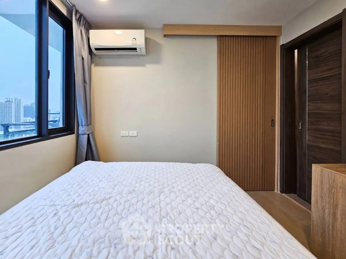 Modern bedroom with city view, featuring a cozy bed and sleek sliding door design.