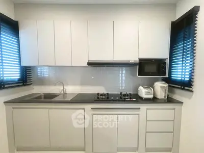 Modern kitchen with sleek cabinetry and gas stove, featuring a minimalist design and ample natural light.