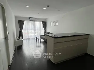 Spacious modern living room with sleek dark flooring and large windows offering natural light.