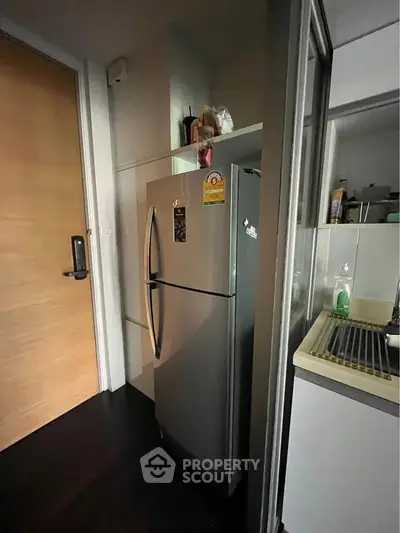 Compact kitchen with stainless steel fridge and modern fixtures in cozy apartment.