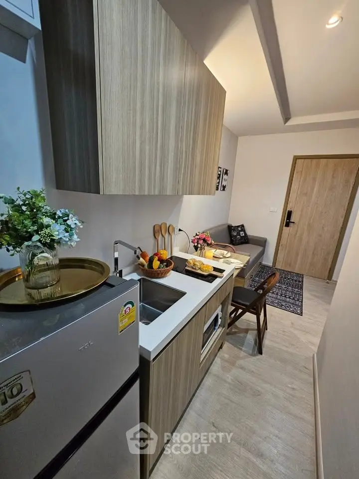 Modern compact kitchen with wooden cabinets and sleek appliances in a cozy apartment.