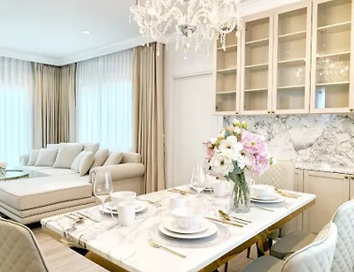 Luxurious open-plan living and dining area with elegant chandelier and marble accents.