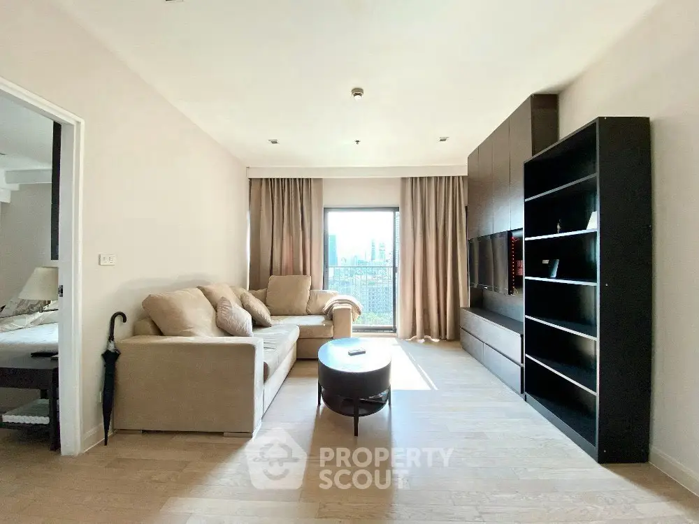 Spacious living room with modern furniture and large window offering city view.
